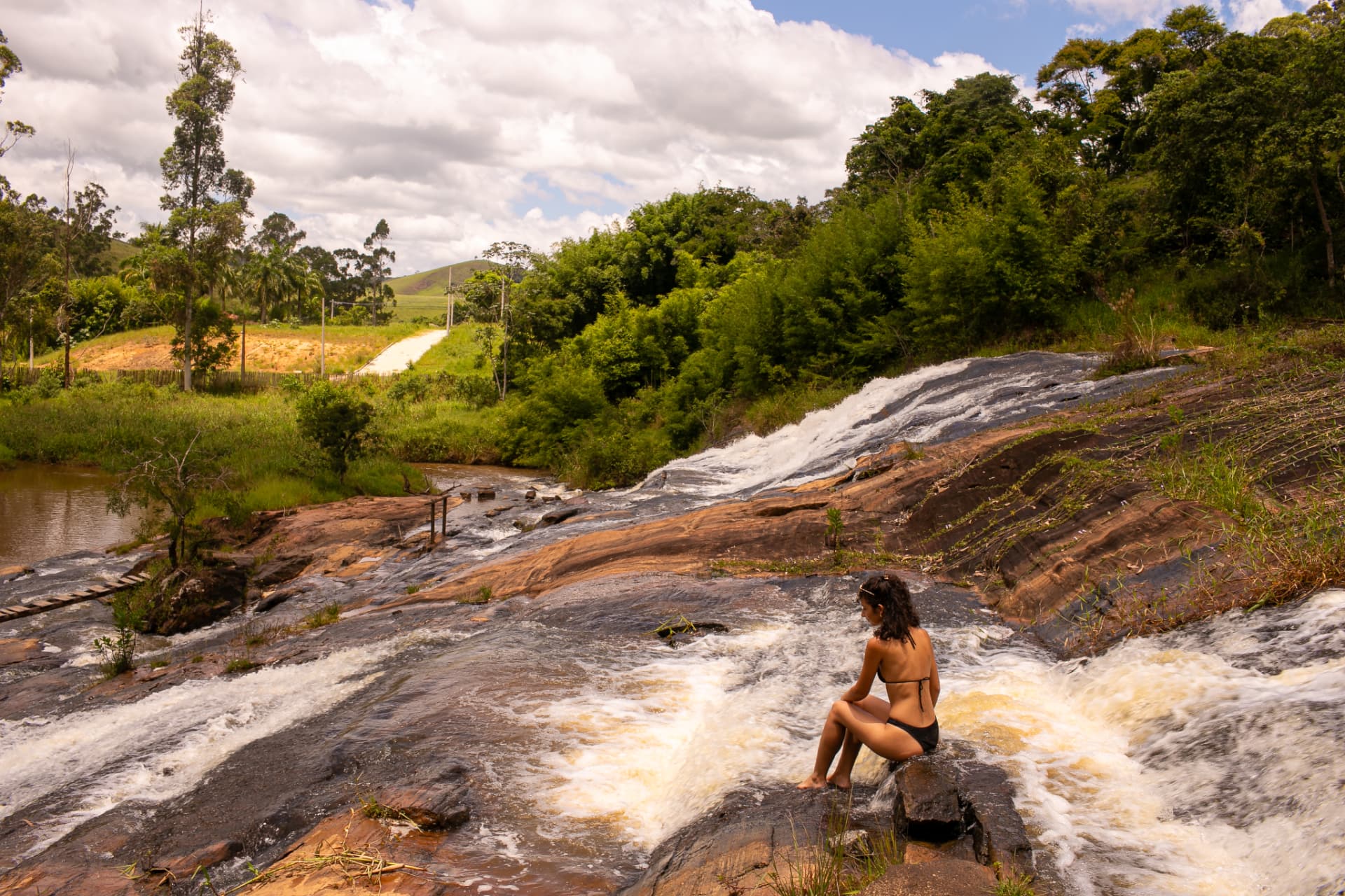 Moradora sentada nas pedras da cachoeira do condomínio